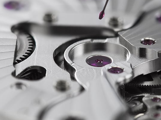 Close-up of a watch mechanism with a drop of liquid being added